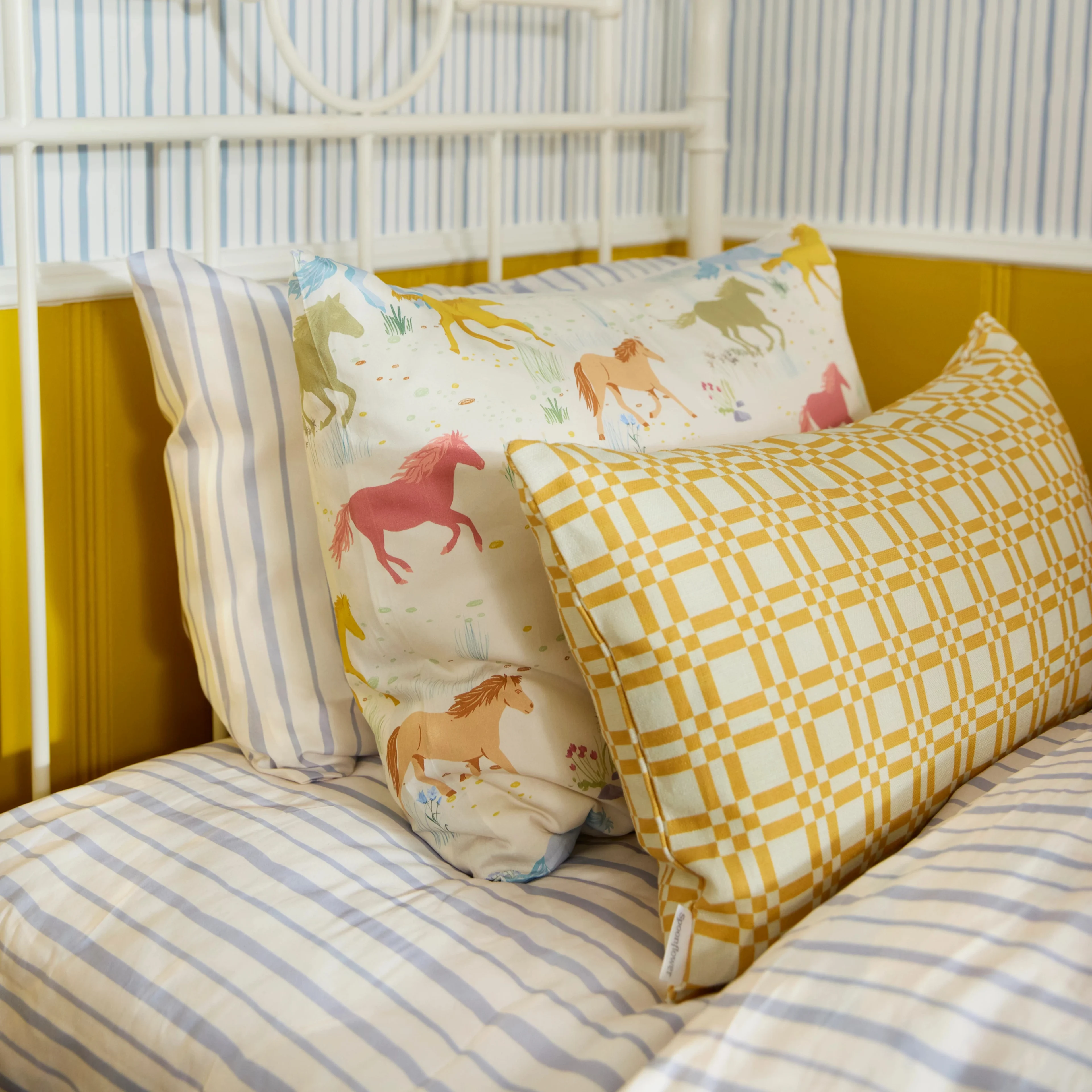 A kids' bed with pillows in Spoonflower pillow shams, accented by a geometric throw pillow.