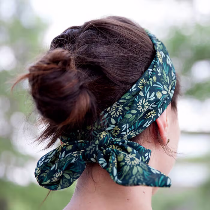Person seen from behind wearing a dark floral headband tied at the back, with hair gathered in a bun.