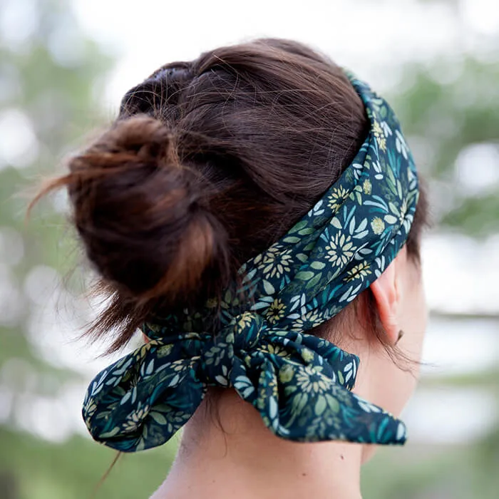 Person seen from behind wearing a dark floral headband tied at the back, with hair gathered in a bun.