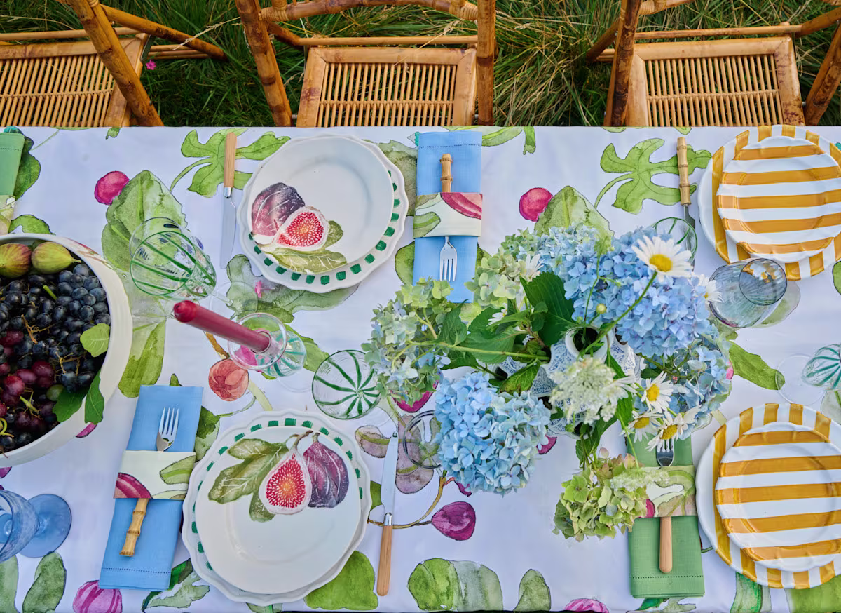 Outdoor table set with fig-patterned linens and blue hydrangeas