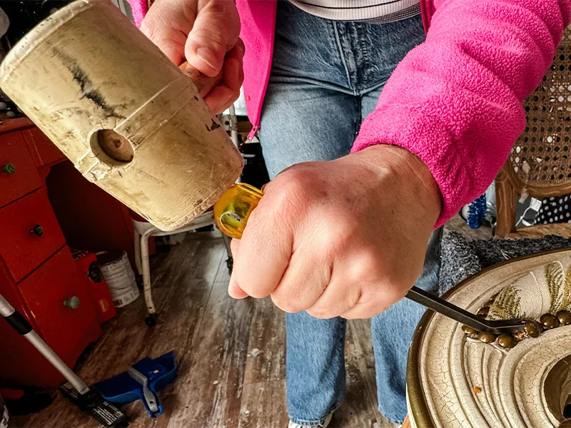 Wendy hammering a staple remover into a chair with a mallet to remove the tack.