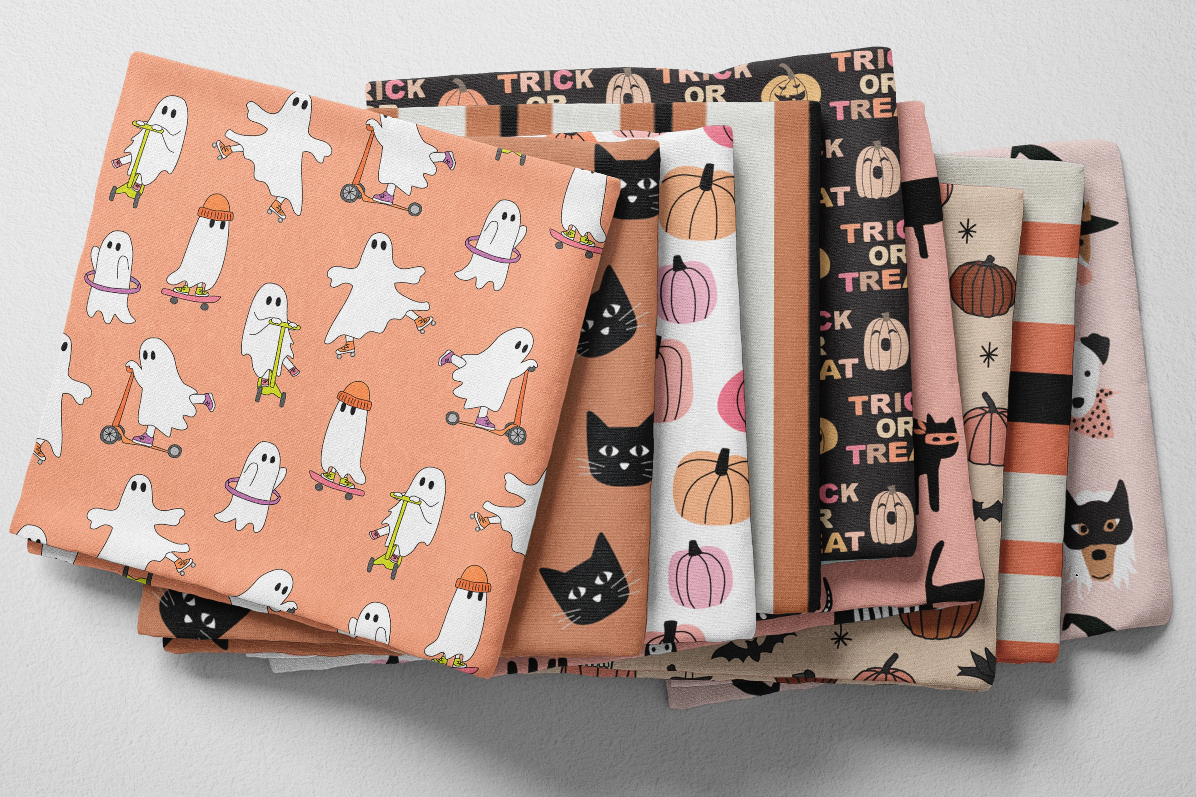 Colorful folded kids' halloween fabric in pumpkin orange, pink, beige, and black