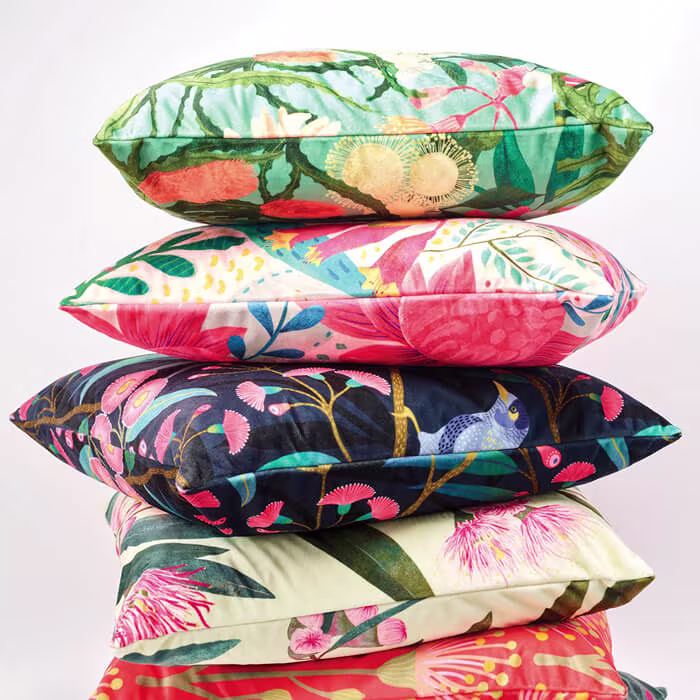 A tall stack of colorful throw pillows with bold floral and botanical prints