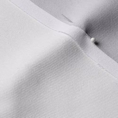 A close-up photo of white fabric with a pin running through it