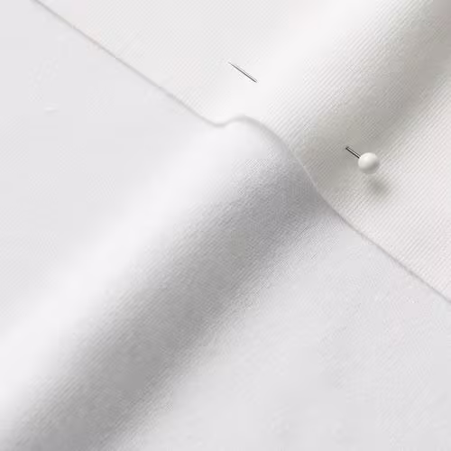 A close-up photo of white fabric with a pin running through it