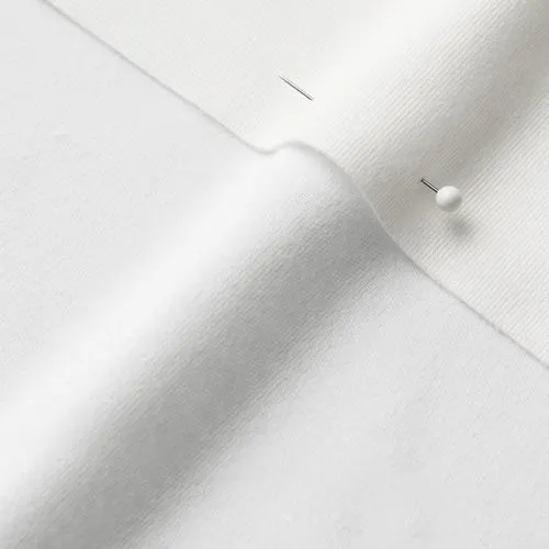 A close-up photo of white fabric with a pin running through it