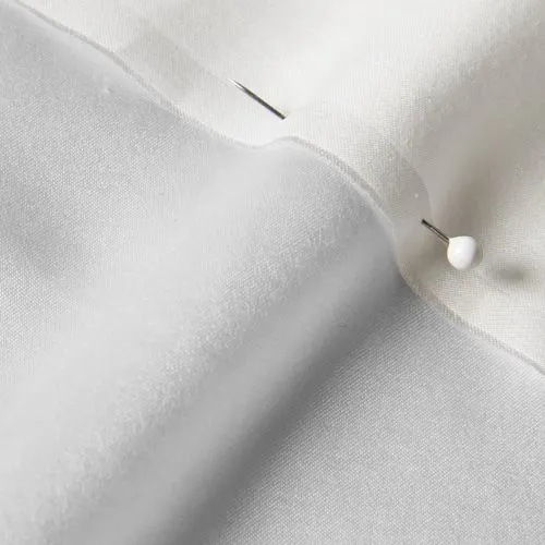 A close-up photo of white fabric with a pin running through it