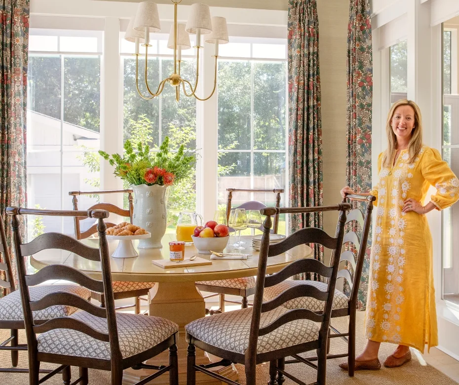 Molly Basile sitting in her dining room with croissants and fruit.