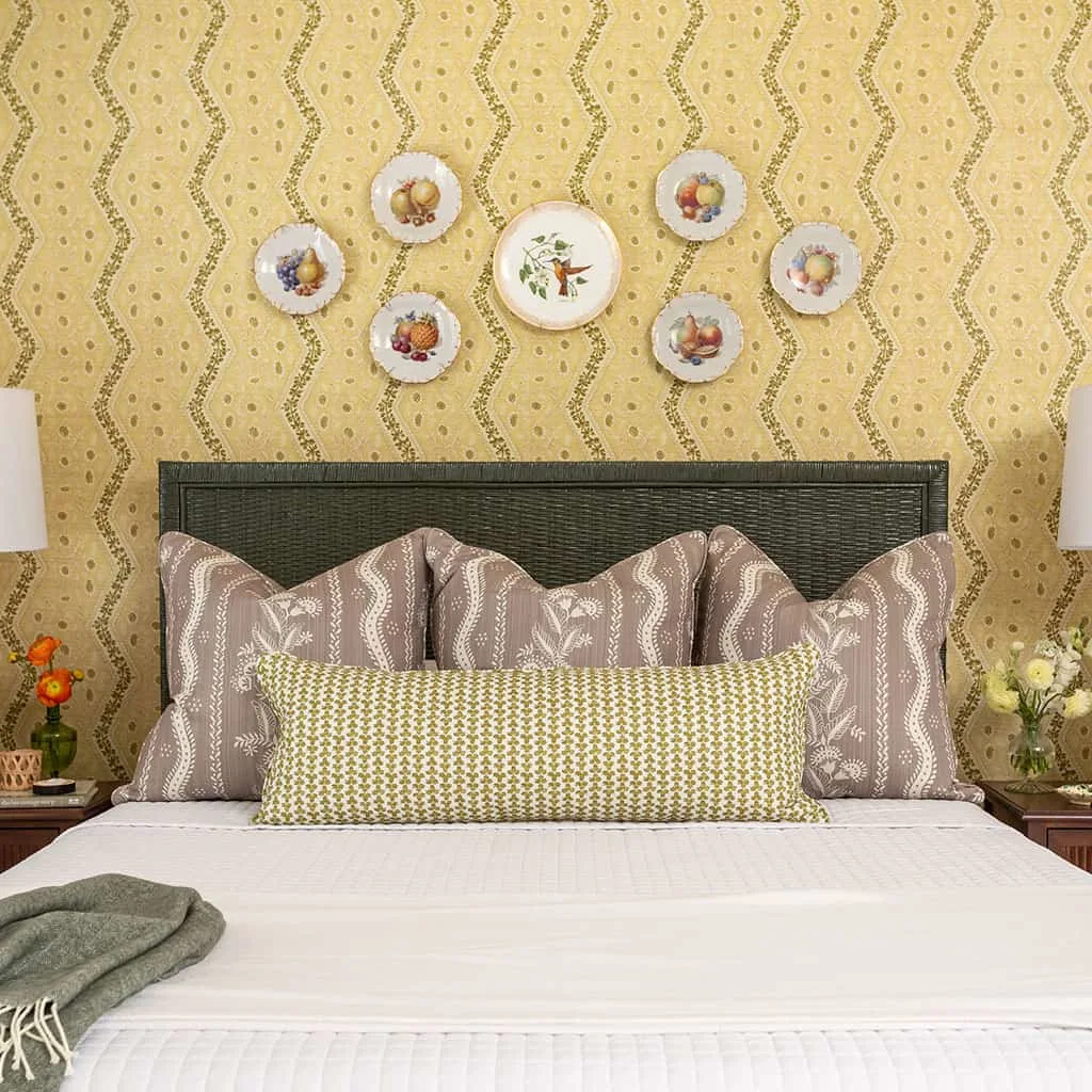 Bed styled with patterned pillows, lumbar accent pillow, and white quilt.
