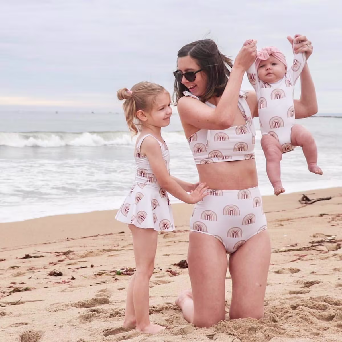 A mum with her children at the beach wearing matching neutral swimwear made with Sport Lycra