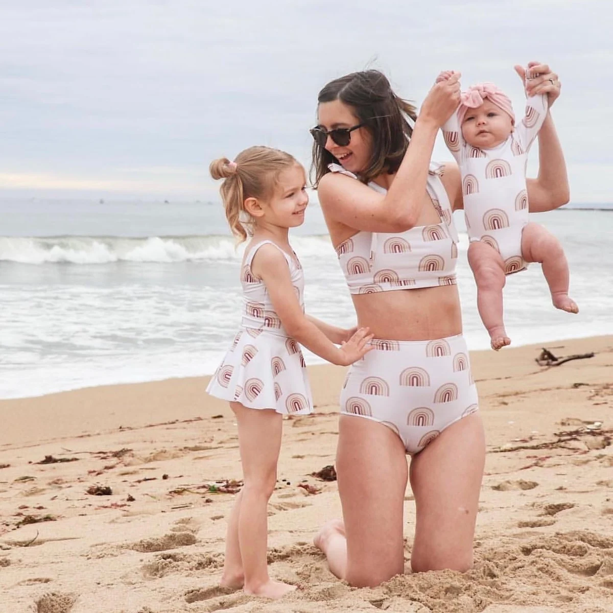 A mum with her children at the beach wearing matching neutral swimwear made with Sport Lycra
