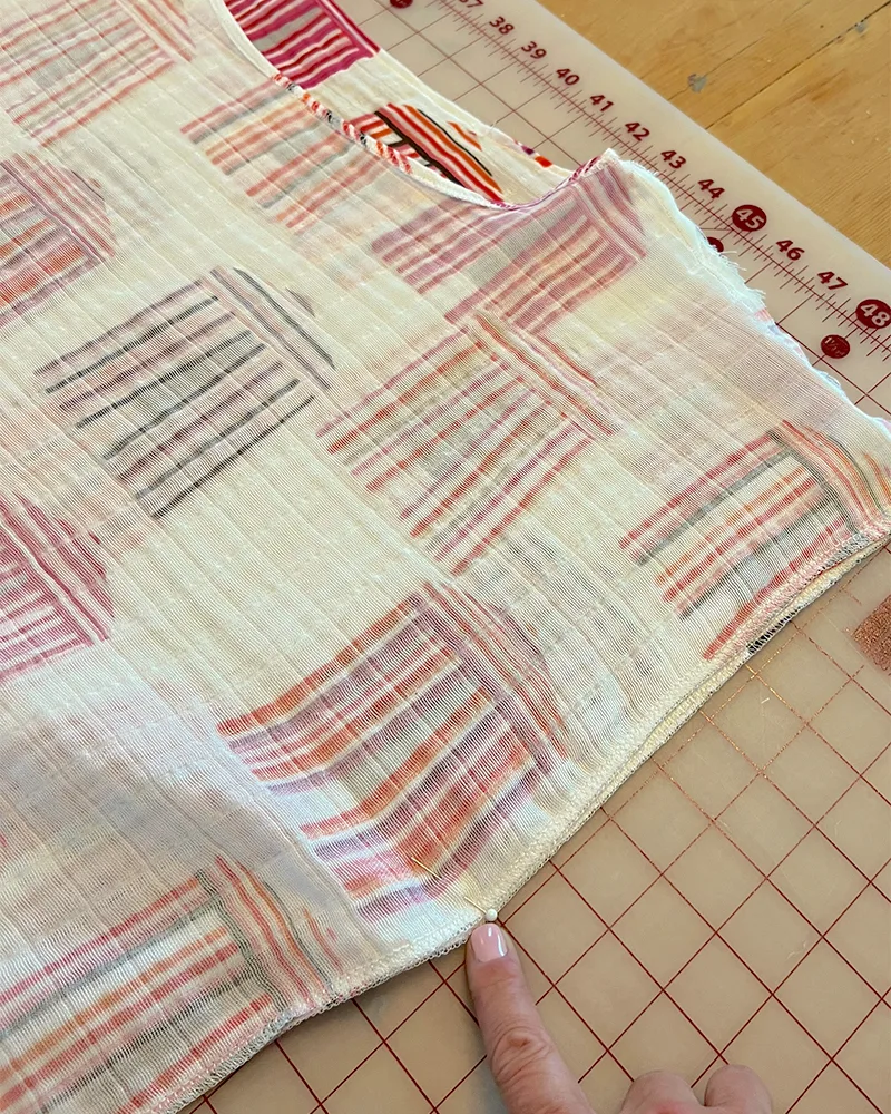 Lining up the caftan's sides and marking the armhole with a pin.