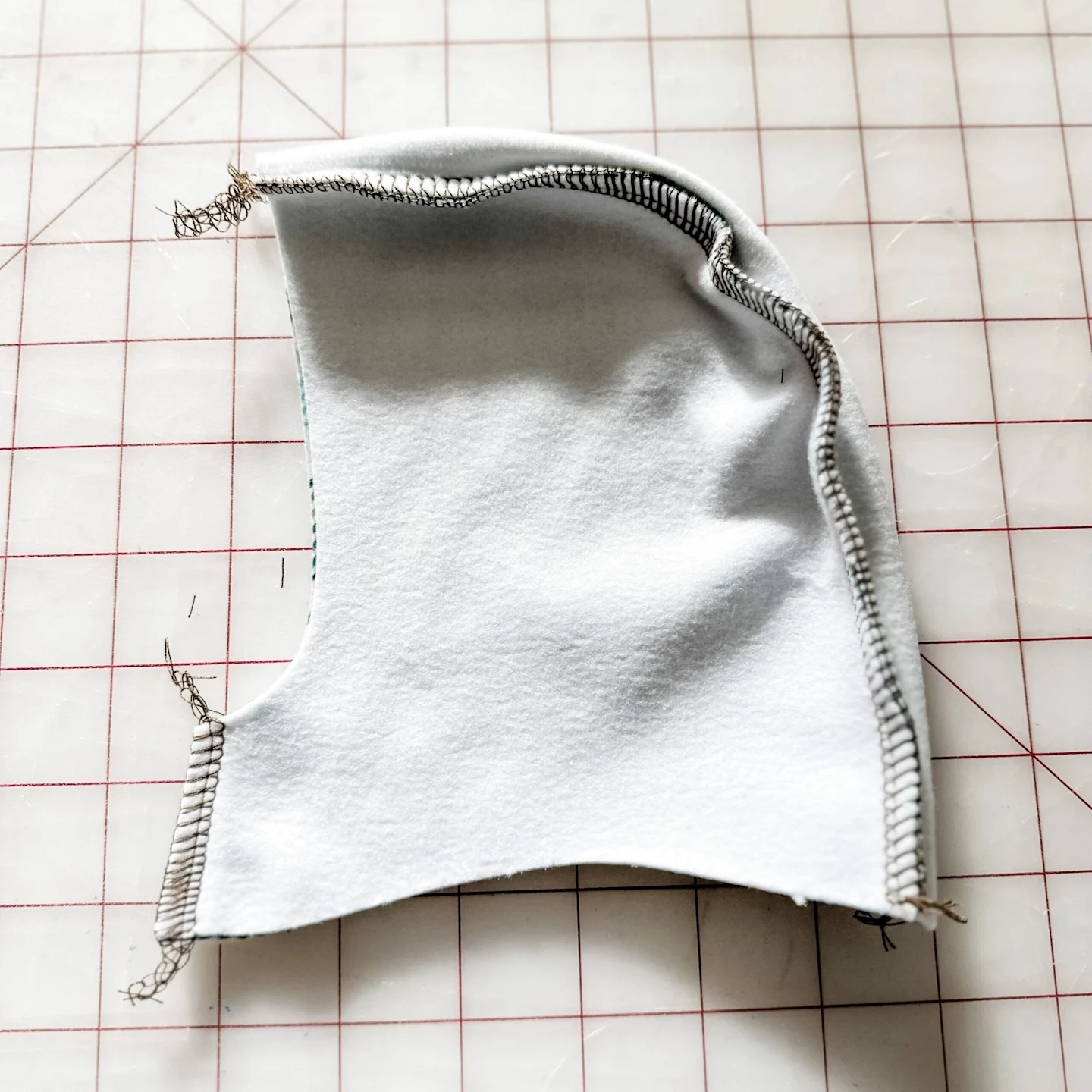 One of the hoodie’s side pieces is shown design side down and sewn to the curve of the center piece. The edges where the sewing clips were are now sewn together.