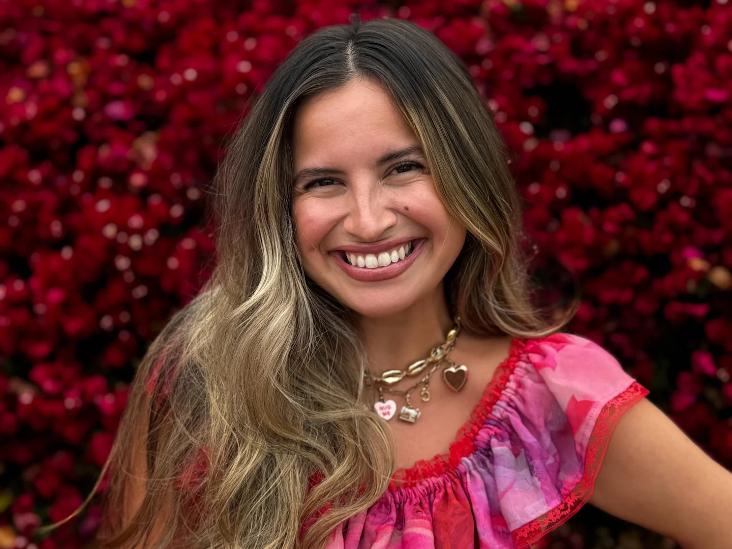 A headshot of Alissah Threads in her handmade vibrant pink and red dress