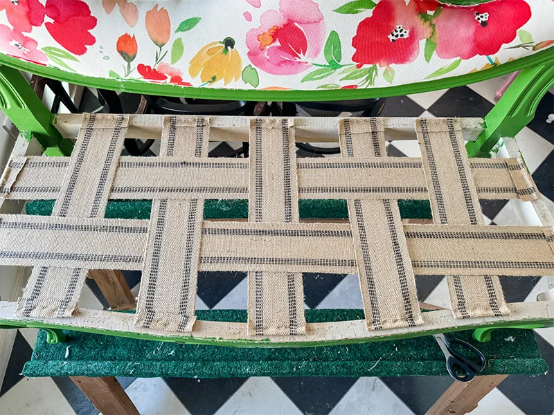Horizontal strips of jute webbing weaved throught the vertical strips of jute webbing stapled to the chair's seat.