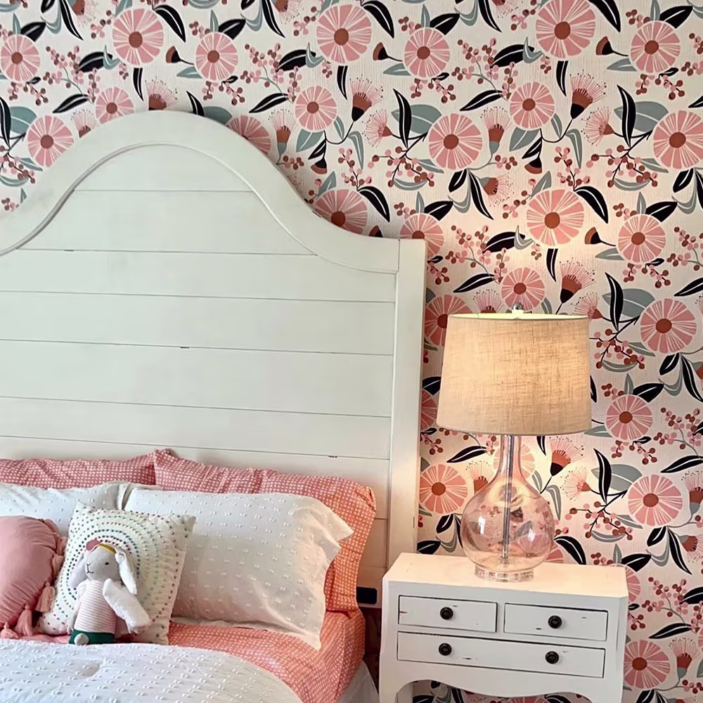 Girls bedroom with pink floral wallpaper behind the bed.