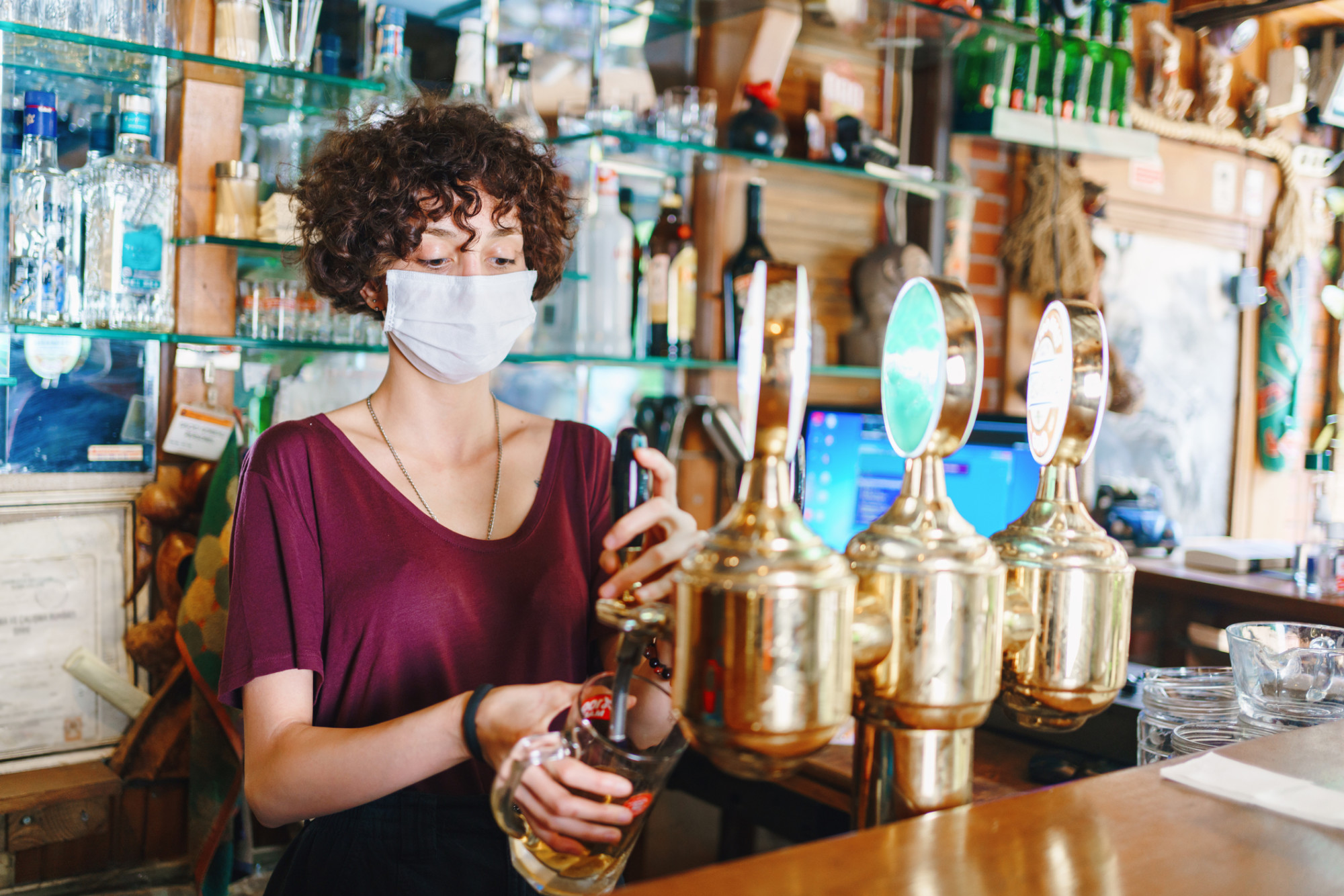 A woman pouring a beer behind a bar