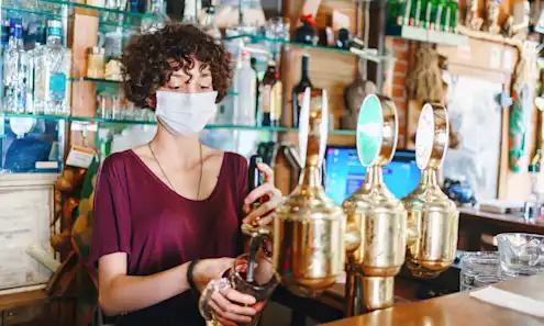 A woman pouring a beer behind a bar