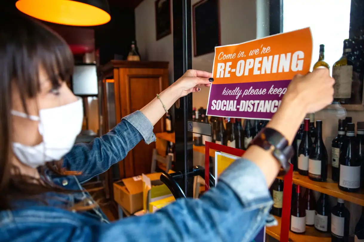 A restaurant owner puts up a reopening sign - COVID-19