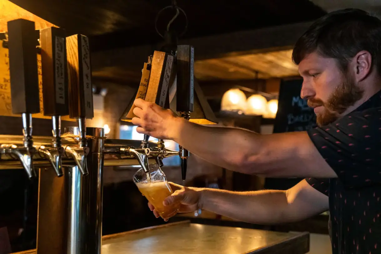 Zach Mack pouring a beer from the tap at a bar. 
