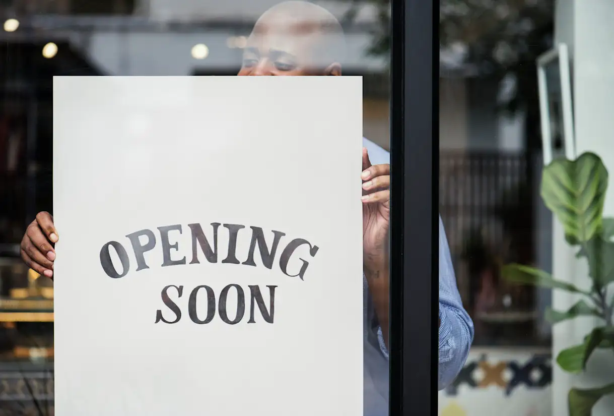 A man puts up an Opening Soon sign