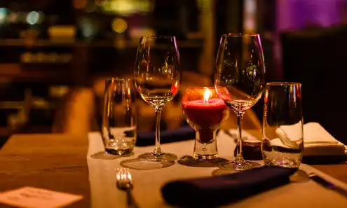 Two water glasses, two wine glasses, and a pink candle in the middle of a restaurant table