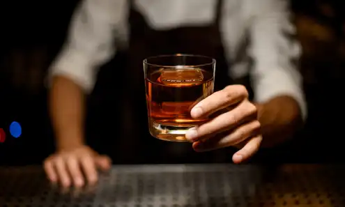 a hand holding a glass of whiskey