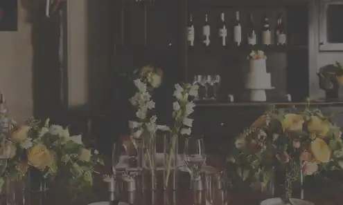 a vase of flowers on a table with wine glasses