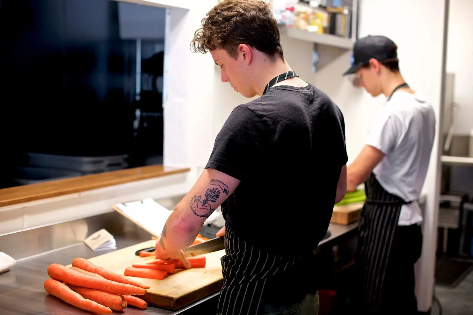 two make chefs cutting carrots in a restaurant kitchen