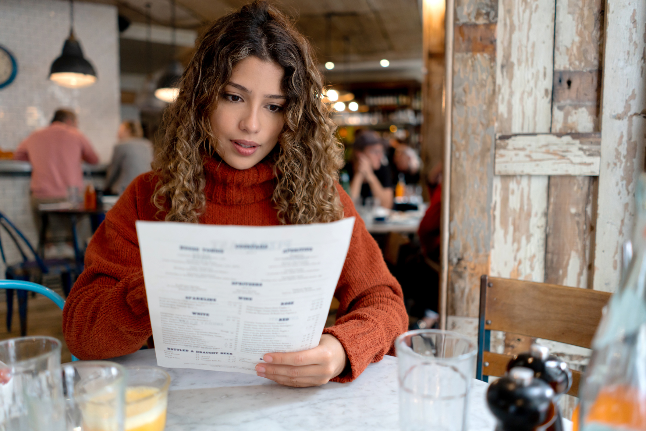 Woman sits at a table in a restaurant and looks over the menu