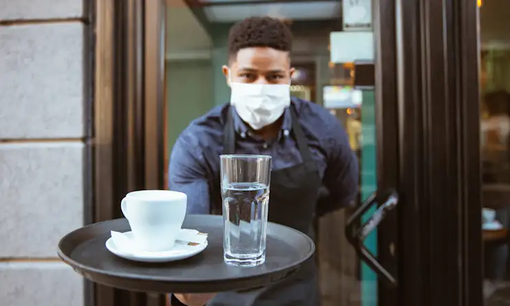 Restaurant staff with a coffee and glass of water on a tray