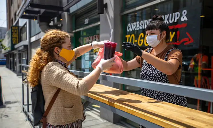 A woman picking up food at a restaurant during COVID-19
