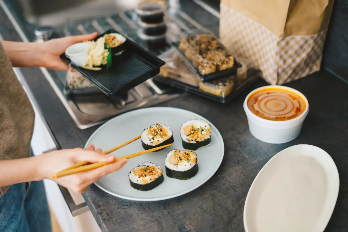 a woman plating sushi from a to-go box