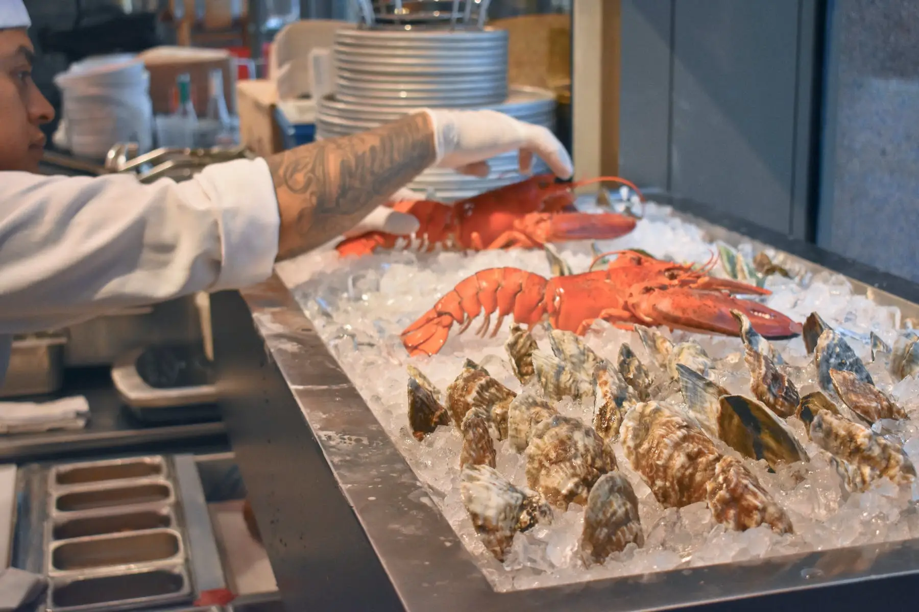A chef in the kitchen with oysters and lobster on crushed ice