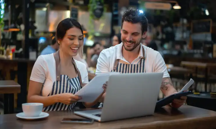 Restaurant owners talking in front of a computer.