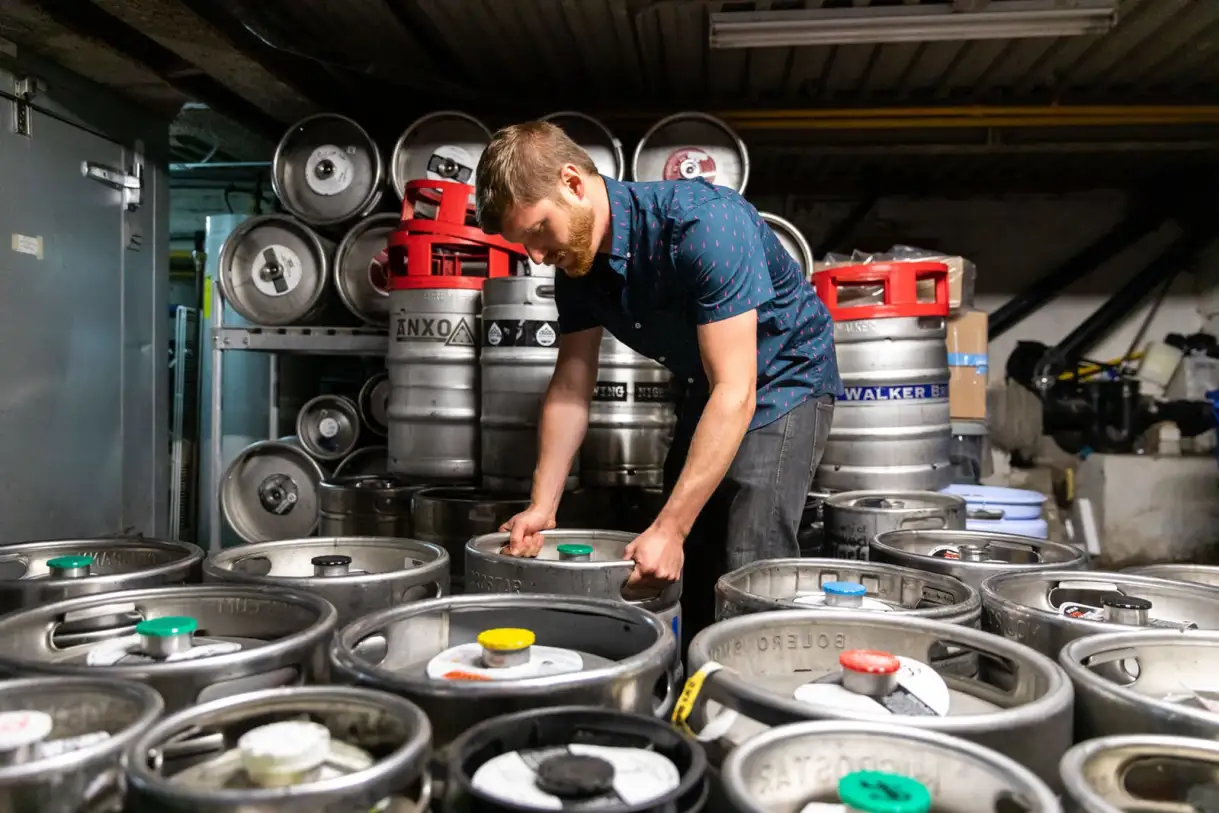 Zach Mack organizing kegs of beer in a basement.
