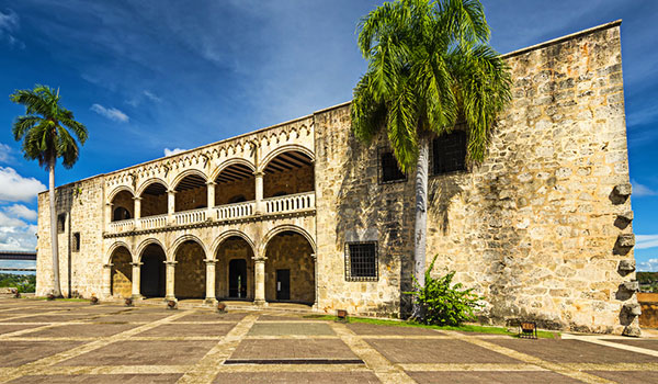 Deux palmiers devant un bâtiment colonial sous un ciel bleu