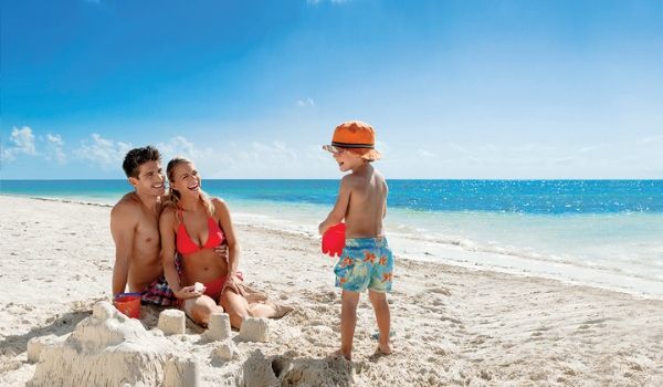 Man, woman and young boy building sandcastle on pristine beach