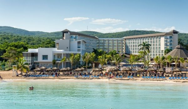 Royalton White Sands resort complex set on a white-sand beach lined with palapas and lounge chairs overlooking the ocean