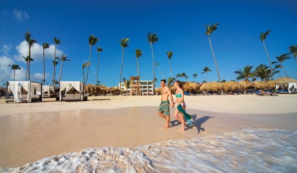 Man and woman holding hands and walking on beach