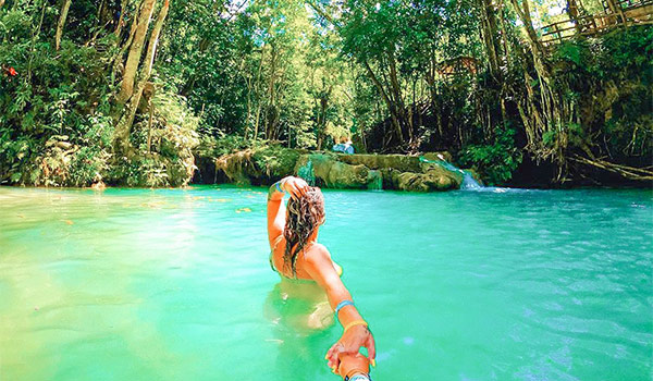 Woman swimming in a turquoise pool surrounded by the lush jungle