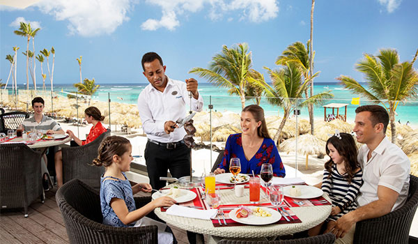 Family enjoying a meal an outdoor terrace overlooking the beach