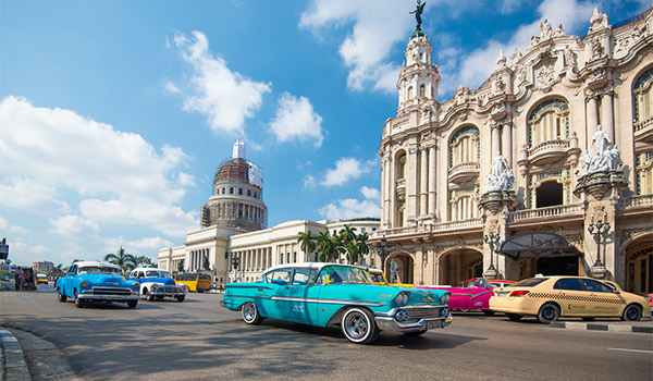 Classic American cars driving past historical buildings