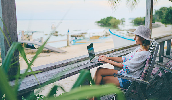 Femme travaillant sur son ordinateur portable sur une terrasse au bord de la plage
