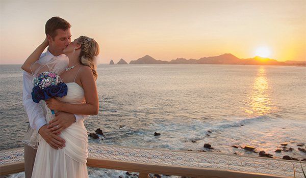 Groom and bride standing on the beach at sunset