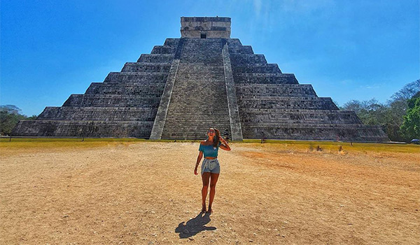 Woman standing in front of ancient Mayan ruins