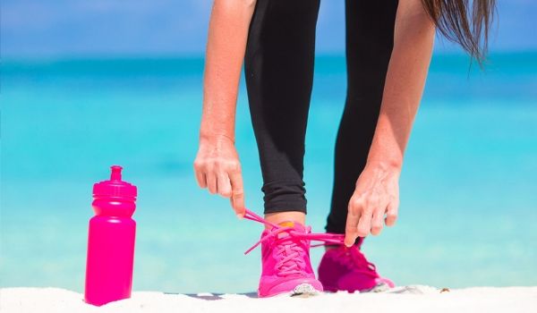Femme attachant ses espadrilles à la plage