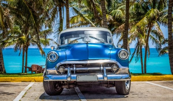 Classic blue American car parked by the beach overlooking the blue water