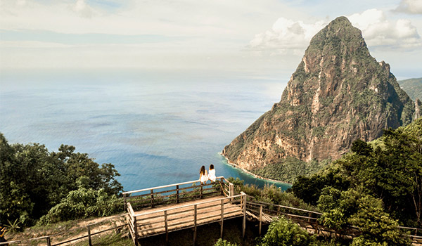 Two people sitting on a bridge overlooking the Piton Mountains