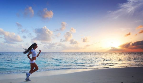 Femmes courant le long de la plage au coucher de soleil